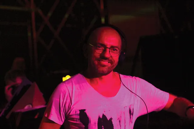 Sven Väth in profile wearing headphones while performing at Mayday in 2014